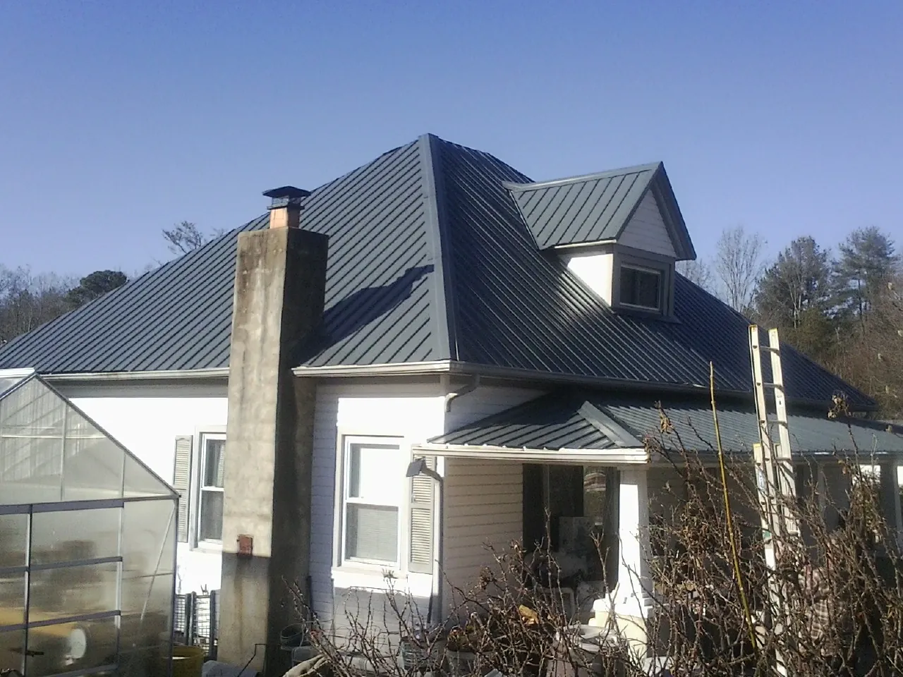 Dark blue standing seam metal roof on a white farmhouse with dormer — Slate & Tile Roof Repair by Roofing Brothers in Indian Orchard