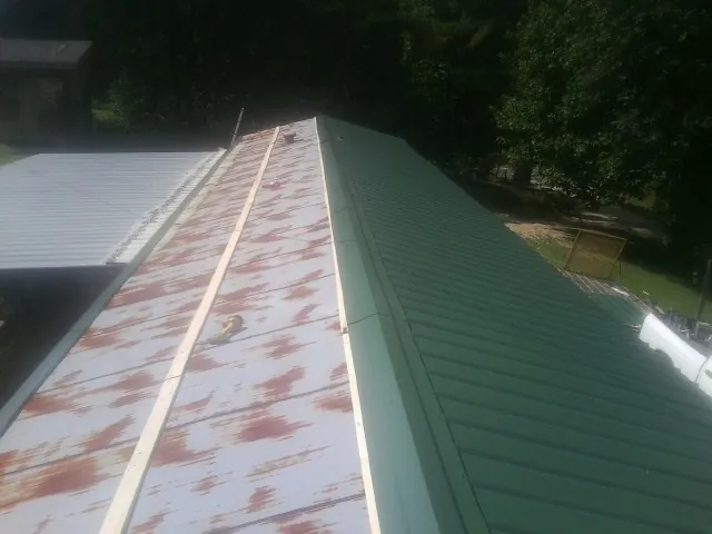 Old rusted panels beside newly installed green metal roofing — Wind Damage Roof Repair by Roofing Brothers in Indian Orchard