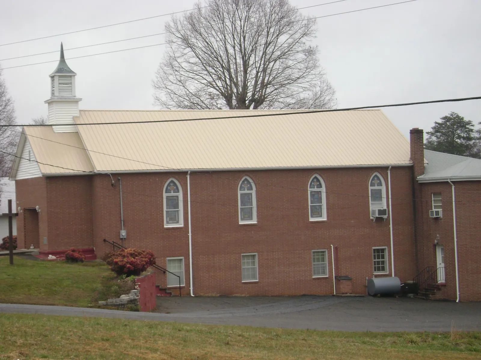 New tan metal roof on a brick church with a white steeple in Indian Orchard