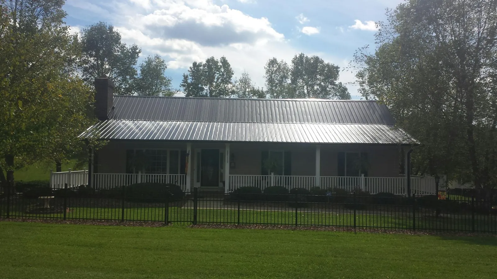 Gray metal roof on a brick ranch with a full width front porch — Gutter Guard Installation work by our crew in Indian Orchard