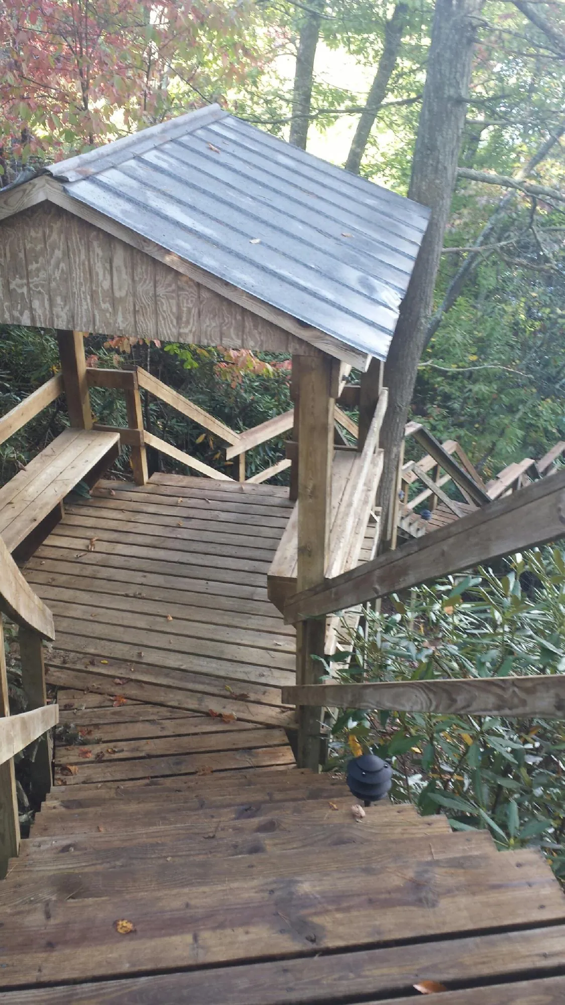 Metal roofed shelter over wooden steps on a wooded walkway — Skylight Repair & Installation work by our crew in Indian Orchard
