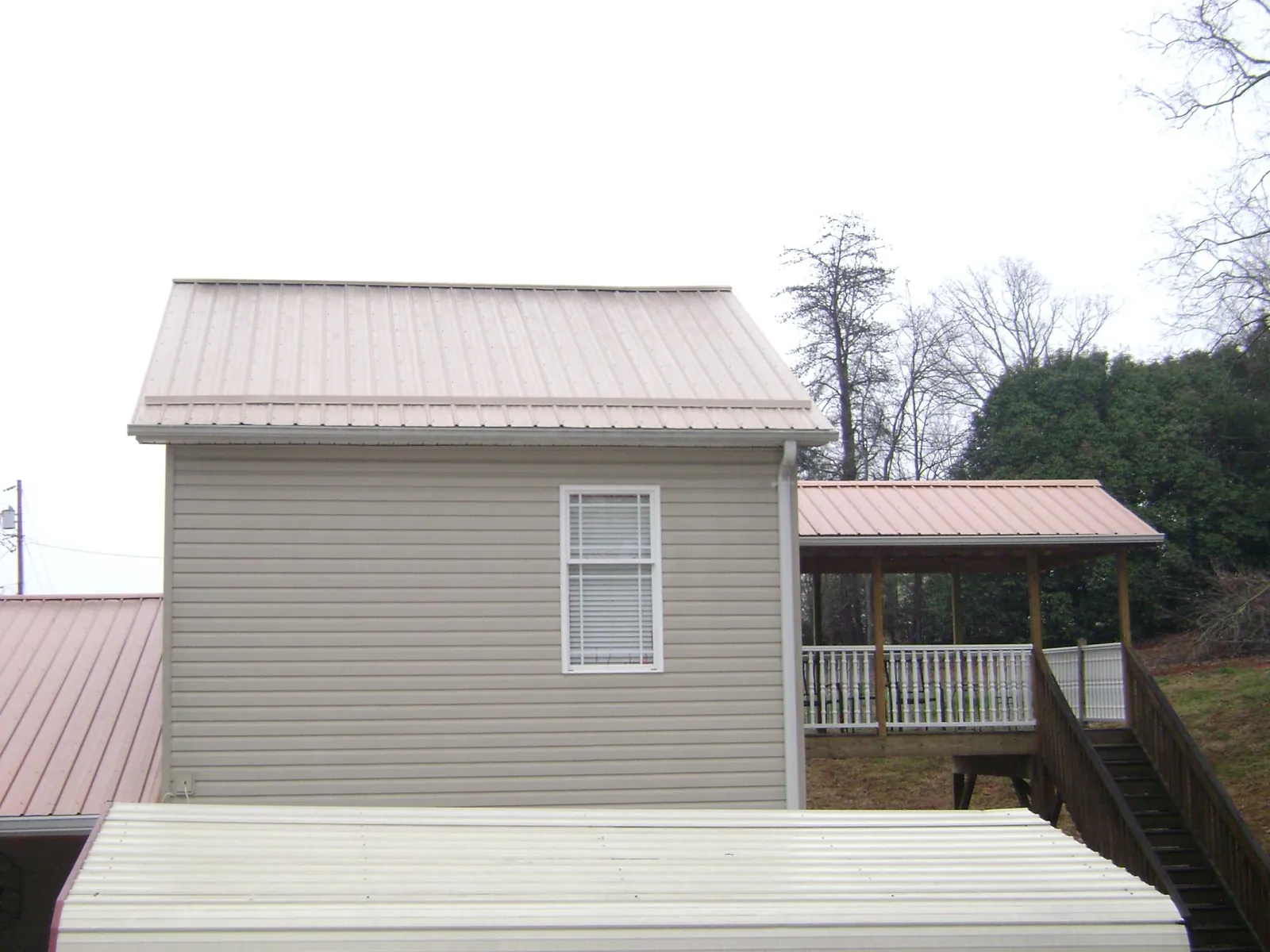 Tan metal roofs on a two story addition and attached porch, from a Roof Replacement job in Indian Orchard