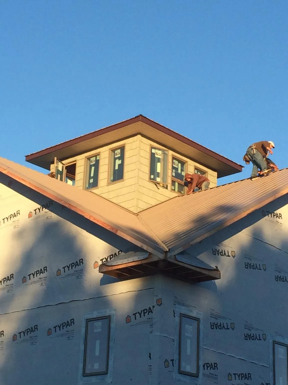Roofers working around a rooftop cupola on a new metal roof at sunset — Roof Waterproofing in Indian Orchard by Roofing Brothers
